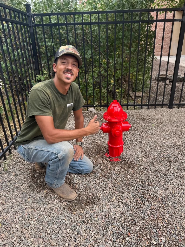 Ponderosa Pathways crew member standing next to fire hydrant during landscaping project at The Grove Apartments.