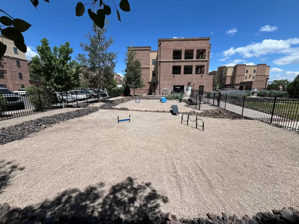 Finished Flagstaff landscaping project showing new dog park with pea gravel, seeded lawn, and equipment at The Grove.