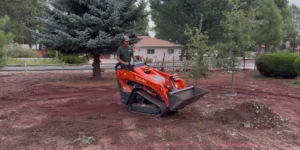 Ponderosa Pathways crew member operating a skid steer during a Flagstaff landscaping cleanup